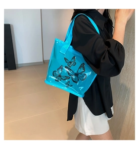 Detailed back view of a blue transparent PVC tote bag with black butterfly print on model