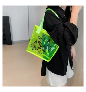 Close-up of fluorescent green transparent PVC tote bag with black butterfly prints and straps