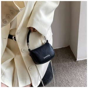 Detailed view of black pebbled leather crossbody bag with silver star rivets on the model