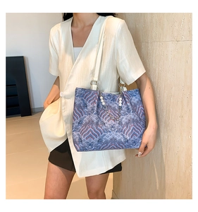 Detailed embroidery on tote bag featuring wave patterns and pearl chain strap