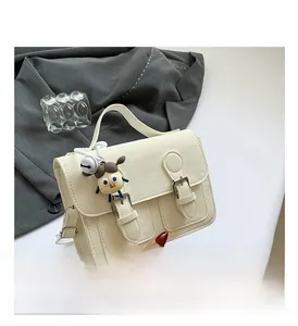 Detail view of cream vintage crossbody bag with dual buckles and cute charm pendant