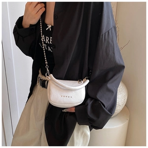 Détail d'un sac demi-lune blanc en cuir avec étoiles argentées et bandoulière chaîne