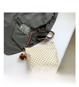 Detail of off-white faux leather tote with embossed geometric patterns and striped strap
