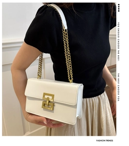 Detailed side view of white minimalist flap bag with golden geometric lock and chain