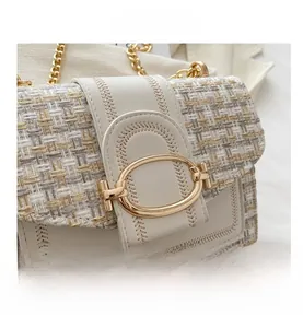 Detail of woven tweed fabric with white leather trim and gold oval metal buckle closure