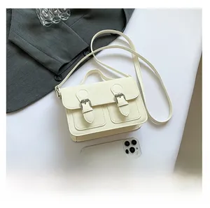 Top-down view of cream PU leather crossbody bag next to smartphone for size comparison