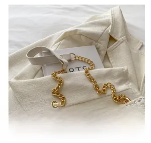 Close-up of woven shoulder bag with gold chain and white leather patchwork strap