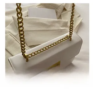 Detail of white leather shoulder bag with gold metal chain and square twist lock buckle