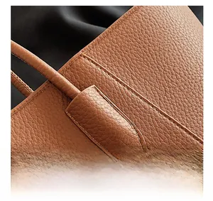 Détail du sac cabas en cuir marron montrant les coutures renforcées et le grain du cuir