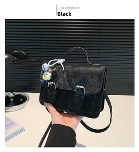 Detail of vintage black satchel bag featuring double buckle flap and cartoon charm