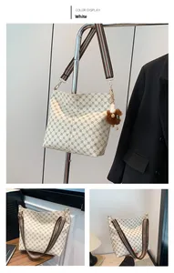 Detail of white monogram tote bag with striped strap and brown plush lion charm