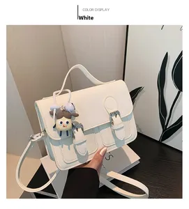 Close-up of white textured leather Cambridge bag with flap buckles and cute pendant