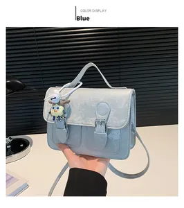 Detail of light blue satchel bag with pearl finish, dual buckles and a cute charm