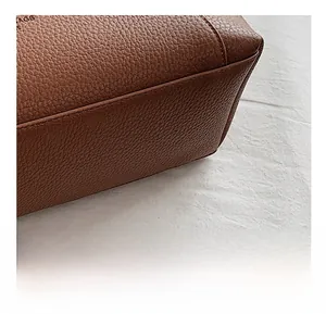 Détail du sac cabas en cuir marron grainé montrant les coutures précises et la texture