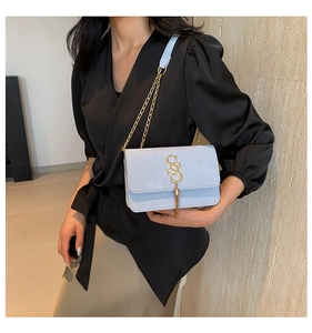 Detailed view of light blue crossbody bag with gold SS logo and tassel ornament