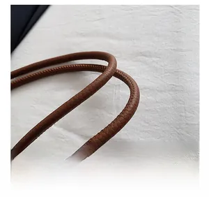 Détail de la bandoulière en similicuir marron avec grain litchi et couture fine