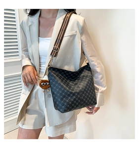 Detail view of black tote bag with geometric pattern and striped shoulder strap
