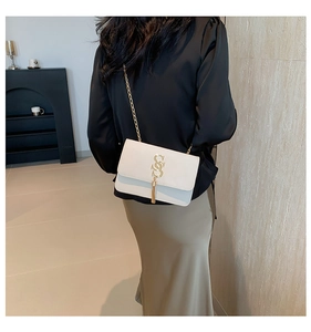 Detailed view of white faux leather bag with gold SS logo and elegant long tassels