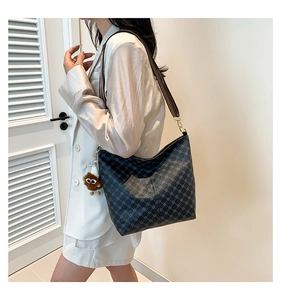 Detail view of retro monogram bucket bag with striped wide strap and plush charm