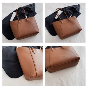 Détail d'un cabas en cuir marron montrant la texture grainée et le logo de mode gravé