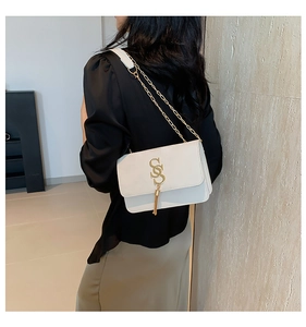 Detail view of white leather shoulder bag with gold S-logo hardware and metal chain strap