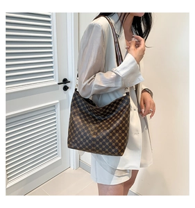 Detail of vintage patterned hobo bag with adjustable striped strap and gold hardware
