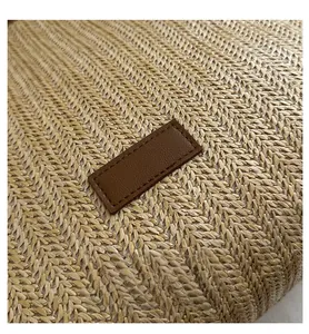 Detail of woven straw texture with a dark brown leather patch and fine stitching