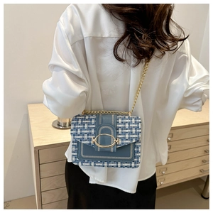 Detail of blue and white plaid crossbody bag with gold chain strap on shoulder