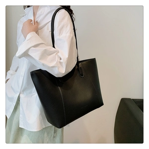 Détail du sac cabas en cuir grainé noir avec des fines anses pour un look élégant