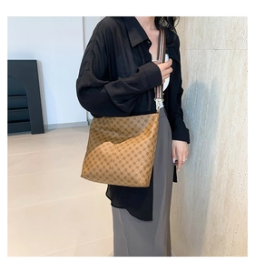 Retro monogram bucket bag featuring a wide striped shoulder strap and leather texture