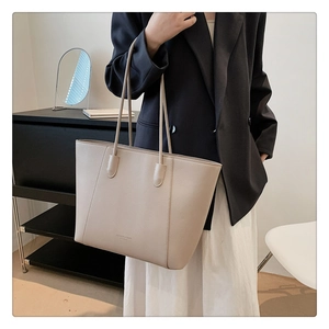 Détail d'un cabas beige avec texture en cuir grainé et logo minimaliste sur le devant