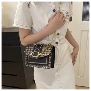 Detail of tweed crossbody bag with gold chain strap and metal clasp on modern outfit