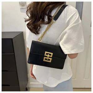 Detail of black leather crossbody bag featuring vintage gold chain and square buckle
