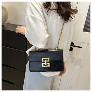 Détail du sac bandoulière vintage en cuir noir avec boucle dorée et bandoulière chaîne