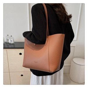 Détail du sac cabas en cuir marron grainé montrant la texture et le logo de la marque