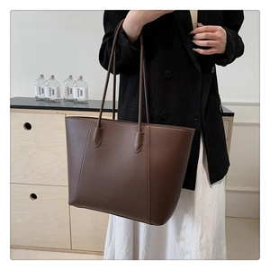 Gros plan sur un grand sac cabas en cuir marron foncé avec texture grainée et fines anses
