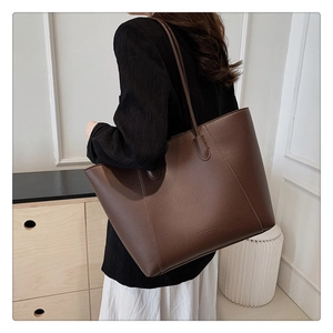Grand sac cabas marron foncé en cuir texturé porté par un mannequin, vue de profil chic