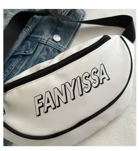 Detail van witte crossbodytas met zwarte FANYISSA-letters op een denim achtergrond