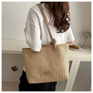 Detail of herringbone weave texture and brown leather strap with knot on straw tote