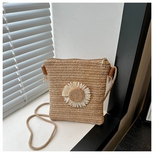 Detail of handwoven straw crossbody bag with white daisy flower and top zipper closure