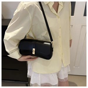 Détail d'un sac à bandoulière noir minimaliste avec boucle dorée et lanière en cuir
