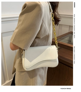 White PU leather shoulder bag with unique curved flap and gold chain strap on model