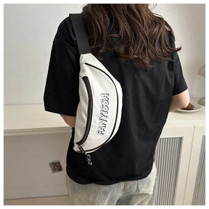 Detailansicht der cremeweißen Oxford-Brusttasche mit schwarzen Riemen und Logo
