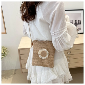Detail of hand-woven straw crossbody bag with large daisy flower on white dress