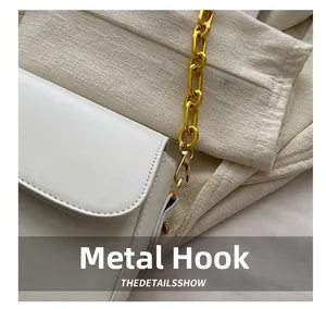 Detailed macro view of high-quality golden metal hook and chain on white leather bag
