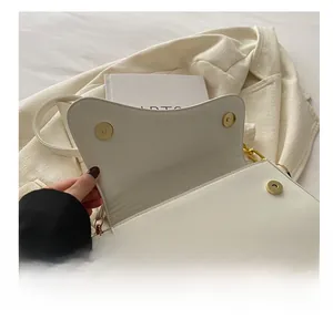 Close-up of white PU shoulder bag featuring golden magnetic snaps and curved flap design
