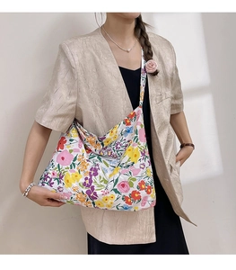 Detailed macro view of a floral canvas crossbody bag featuring colorful summer patterns