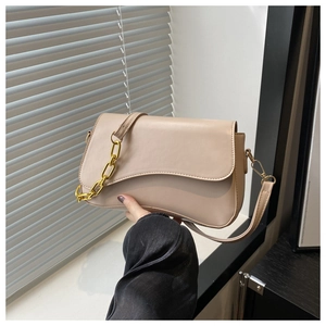 Detail of minimalist beige crossbody bag featuring a thick gold chain strap and smooth faux leather