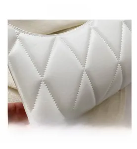 Detail view of white quilted faux leather texture with elegant diamond stitching on handbag