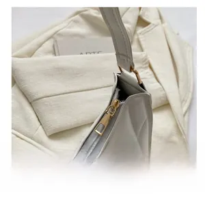 Close-up of beige quilted shoulder bag with smooth golden metal zipper and texture